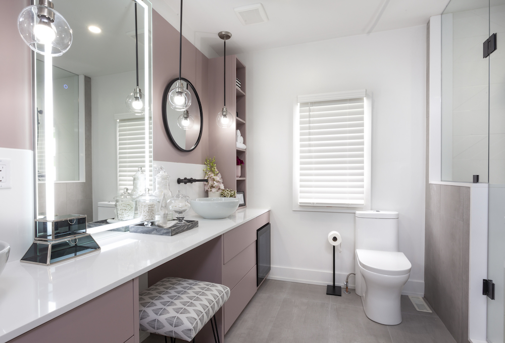 Chic bathroom with a large white vanity, pink cabinets, a white toilet and a makeup fridge