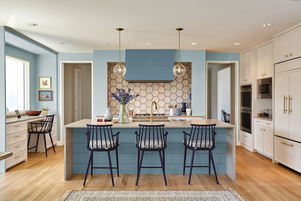 Beautiful kitchen painted in two tones of blue from BEHR with a large centre island with three navy blue barstools
