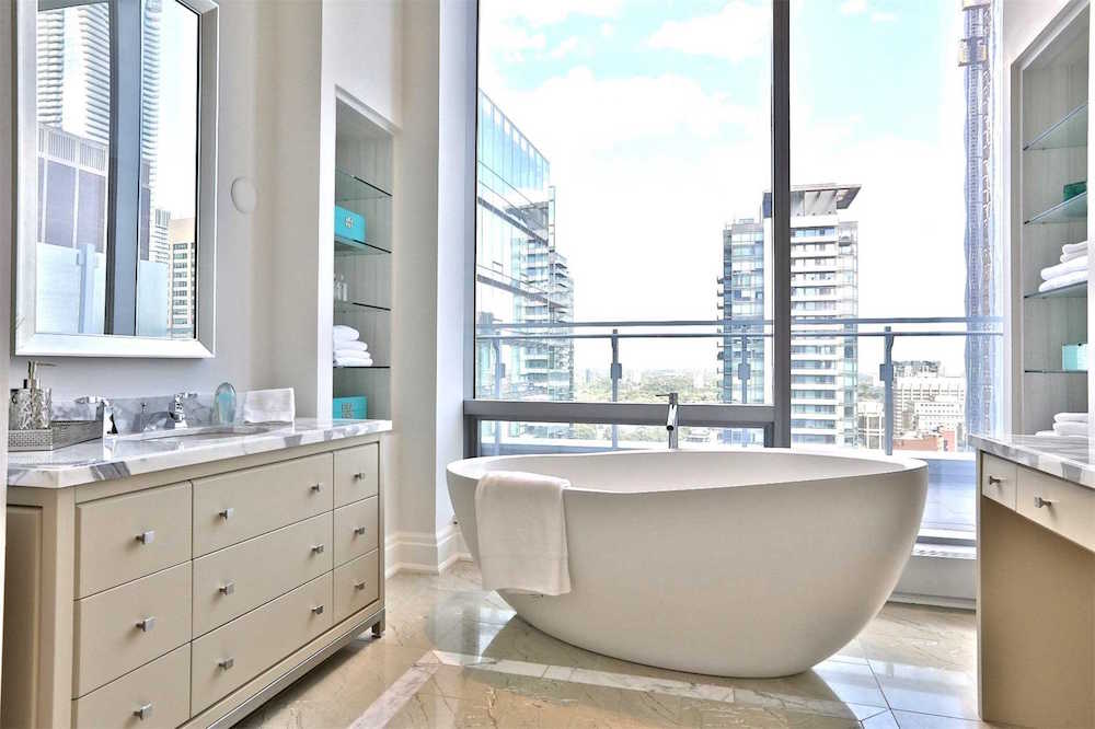 modern white bathroom with freestanding bathtub and and windows with city view