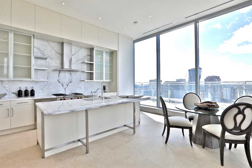 modern white kitchen with marble backsplash and windows with city view