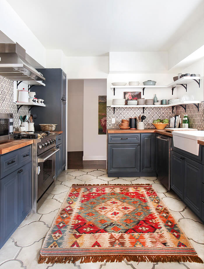 Bohemian-inspired kitchen with dark blue cabinetry and bold floor tiles.
