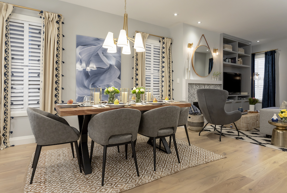 Six grey upholstered dining chairs surround a chic wood dining table in an open concept living space