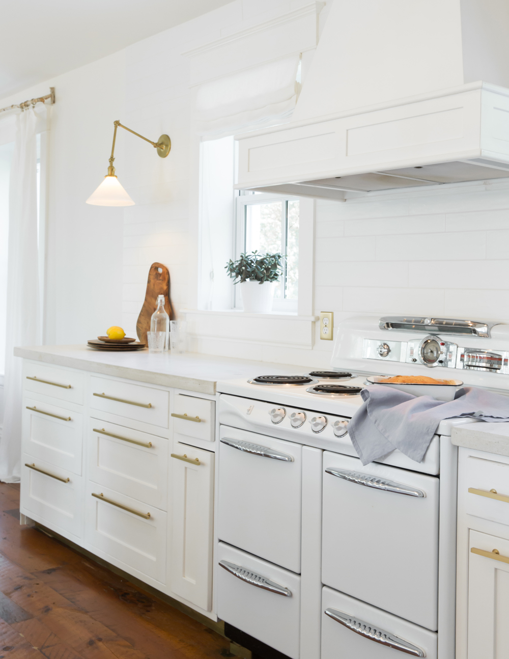 White kitchen cabinets with gold pulls and vintage stove