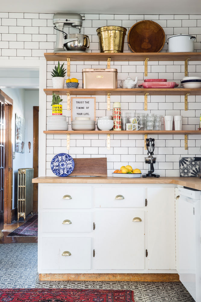 Stylish kitchen with walnut open shelving featuring gold brackets.