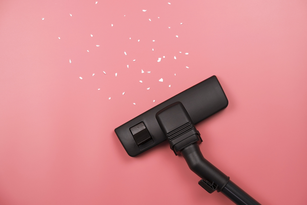 Close-up of a black vacuum cleaner on pink wall to show cleaning walls before painting