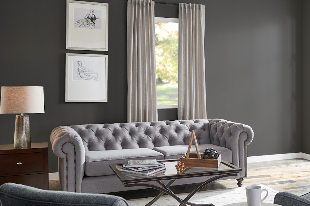 Chic living room with a tufted grey couch, modern coffee table, two frames on the wall, light grey drapes and walls painted in BEHR Liquid Mercury N510-5 and White 52