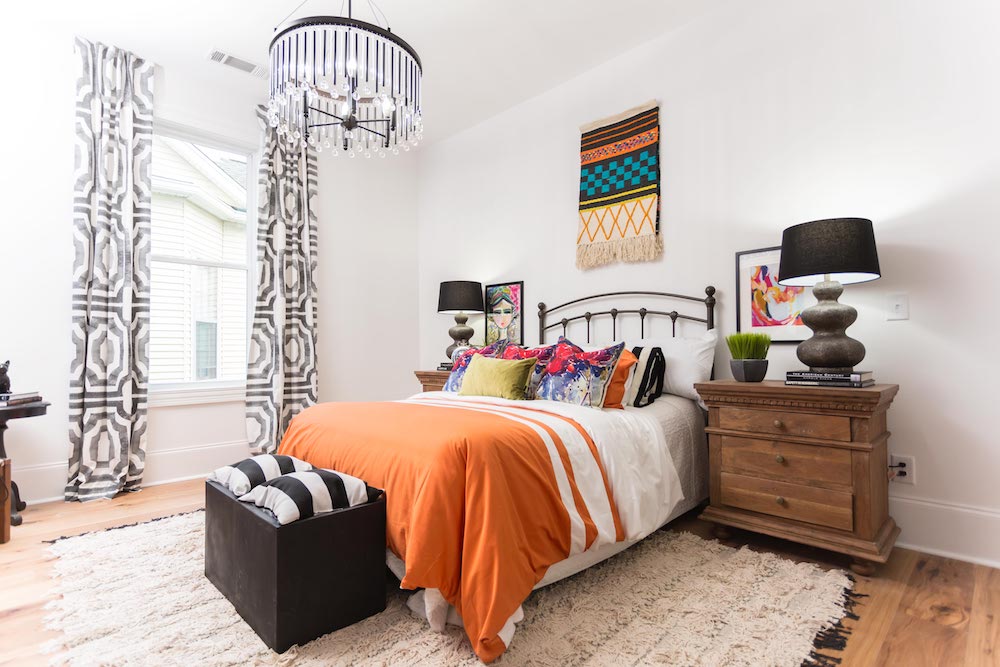 Masters of Flip bohemian Victorian house master bedroom bed with orange striped bedspread, black and crystal chandelier and large white rug