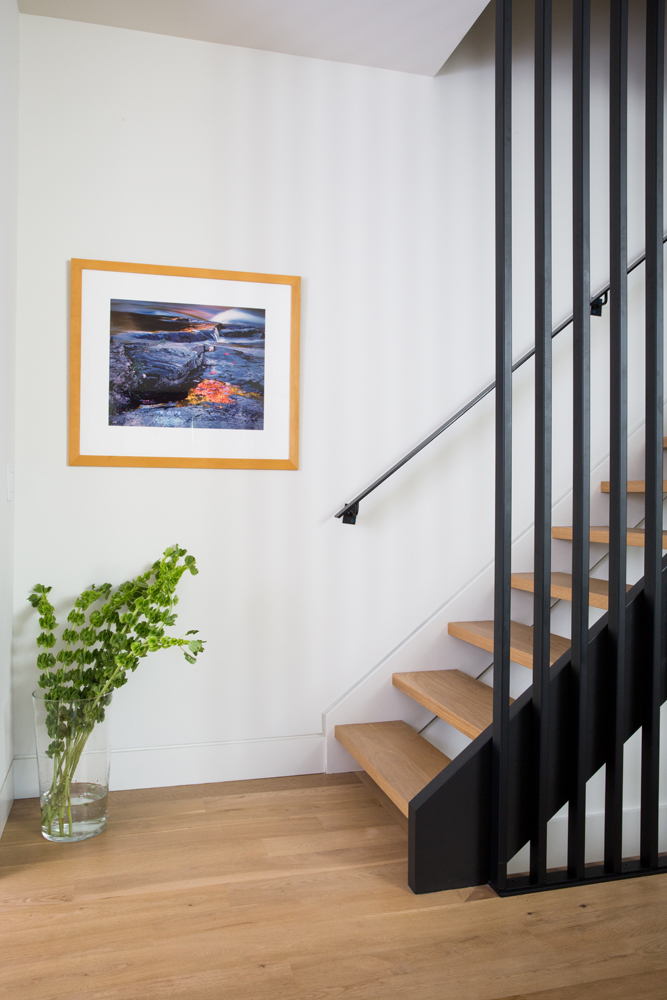 Framed artwork at bottom of staircase in dining room