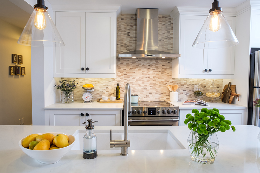 White modern kitchen with quartz countertops and white shaker cabinets in a renovated farmhouse