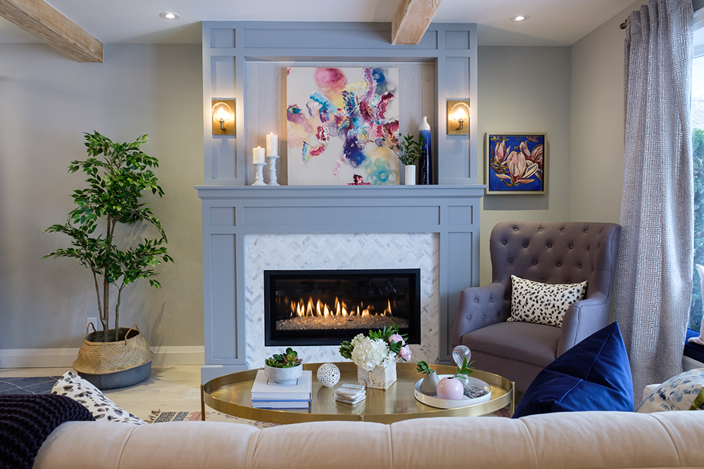 Stylish gas fireplace sits in a grey feature wall with wood mouldings and colourful painting