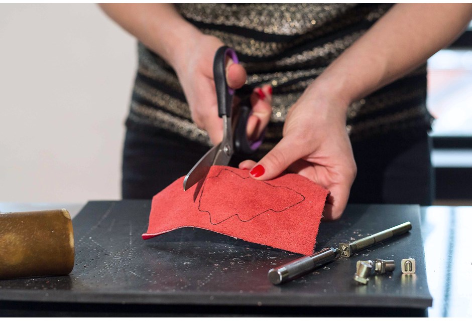 Women cutting out leather shape in shape of treee