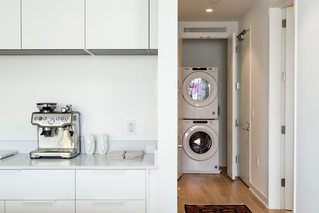 Photo of a home interior including a section of a kitchen and a stacked washer/dryer unit.
