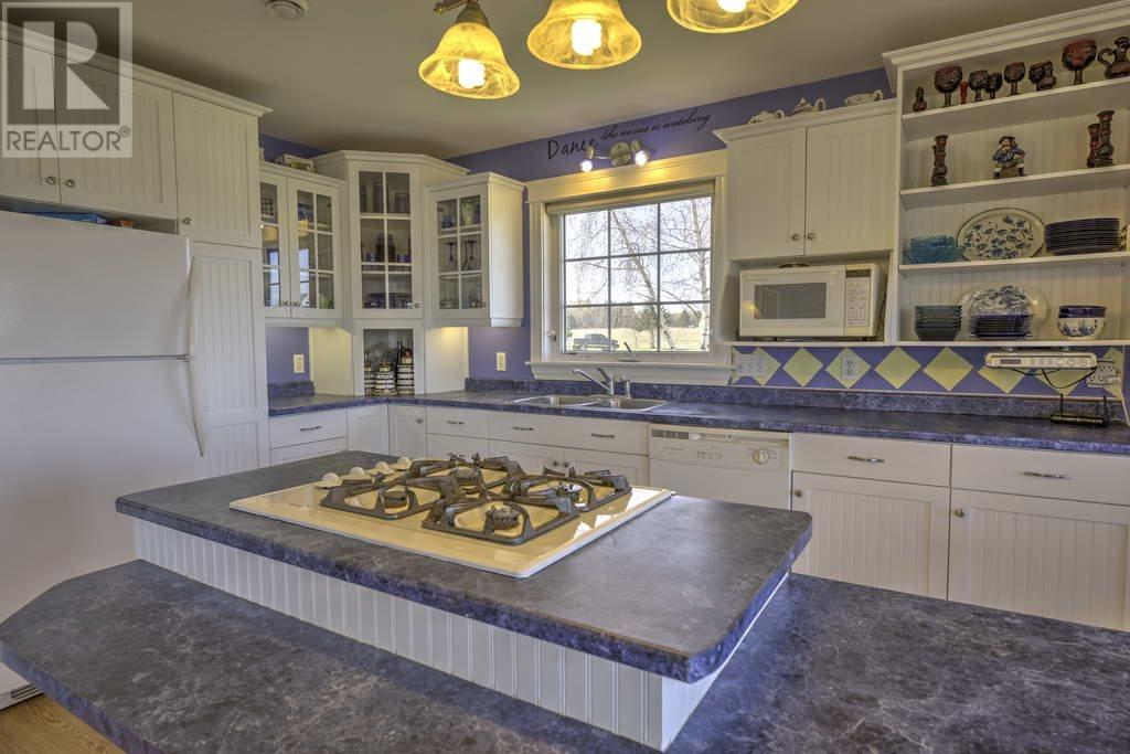 Spacious kitchen with lavender walls and large marble island with burners on top
