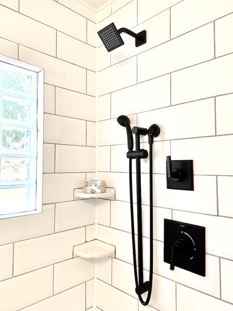 Beautiful modern shower with large white subway tiles, glass block window, and matte black shower hardware and head