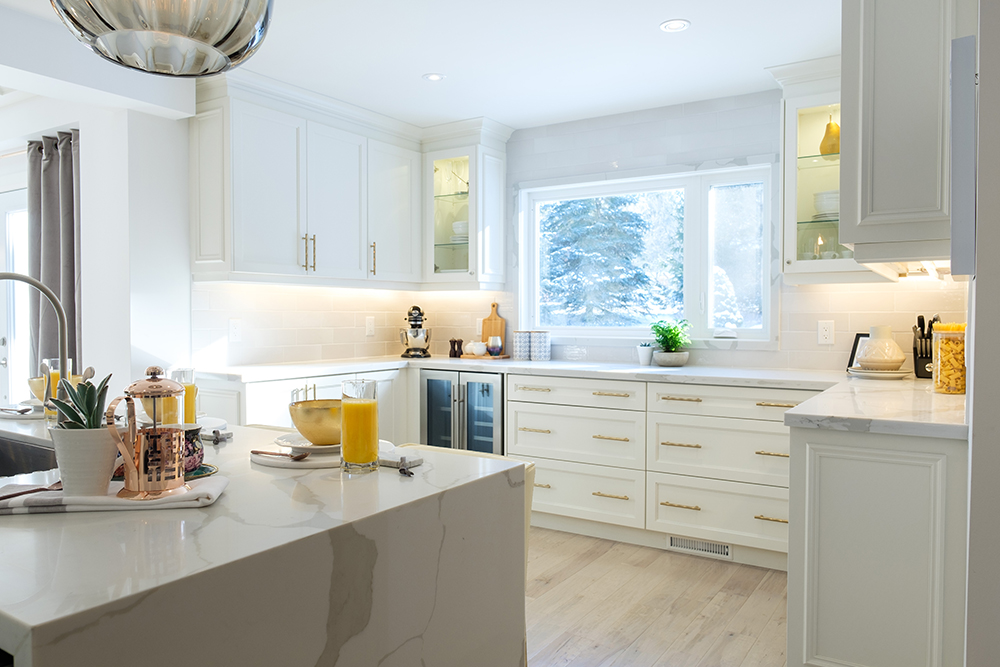 Modern white kitchen with centre island and white shaker cabinets with gold pulls