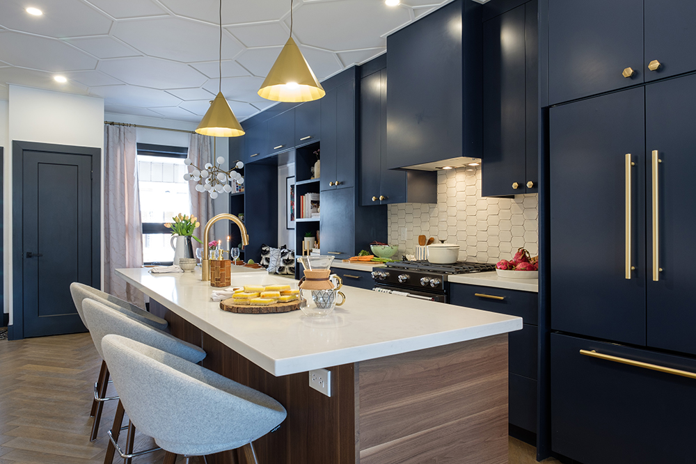 Mid century modern kitchen with large centre island, grey egg shaped bar stools, two gold pendant lamps and dark blue cabinetry