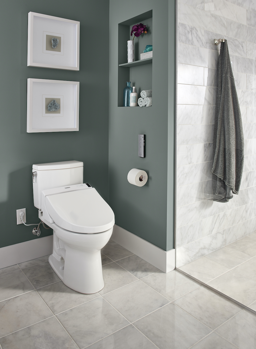 Beautiful bathroom with grey and white tile floors, walk-in shower with grey and white tiles, green grey painted walls, and Toto Washlet® C200 Bidet Toilet Seat with PreMist™, found at Splashes Bath & Kitchen, with two framed paintings above it
