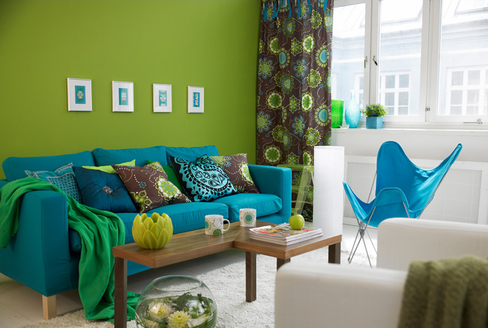Bright green wall paint in a bold living room featuring a blue couch, narrow coffee table and potted plants