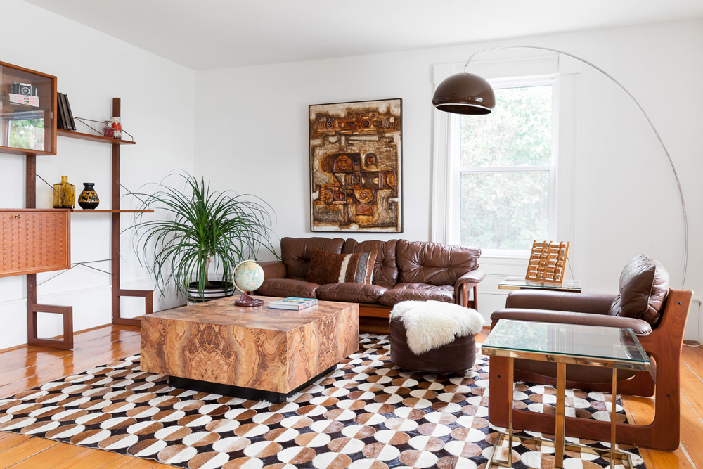 A retro living room featuring brown furniture, floor lamps and abstract wall art