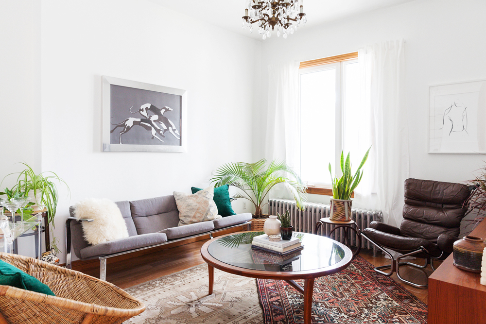 A circular glass coffee table in a retro living room featuring neutral furniture and carpets