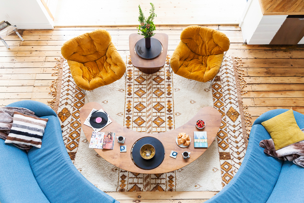 Bold blue and yellow furniture in a retro living room outfitted with potted plants, LPs and throw pillows