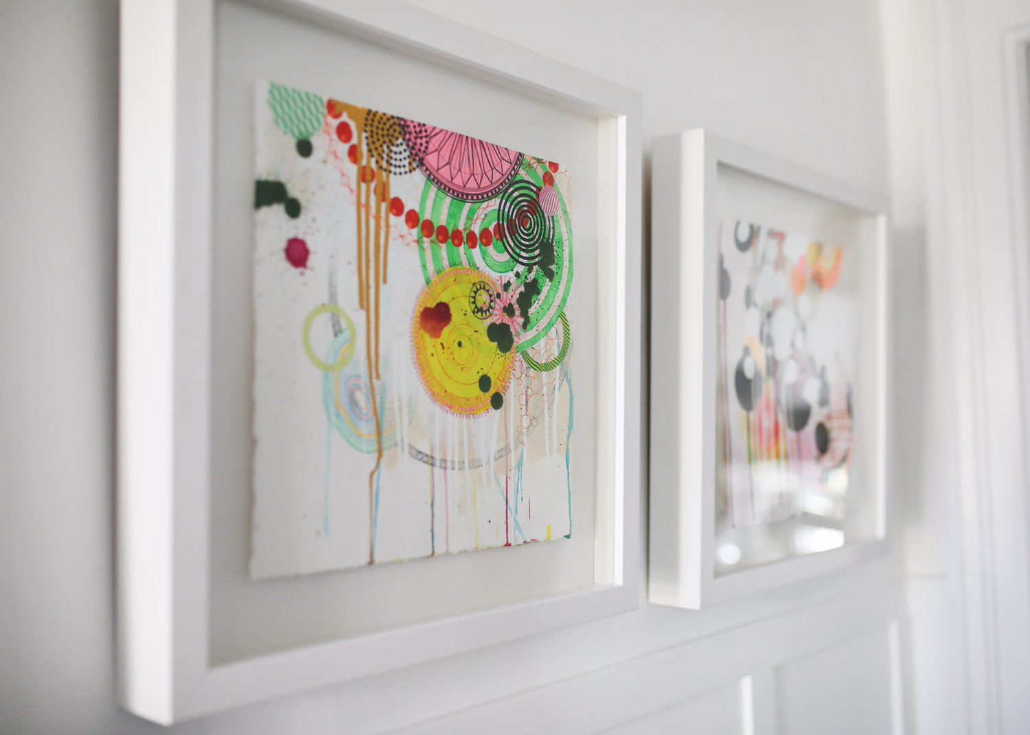 Colourful artwork in white frames hanging on wall
