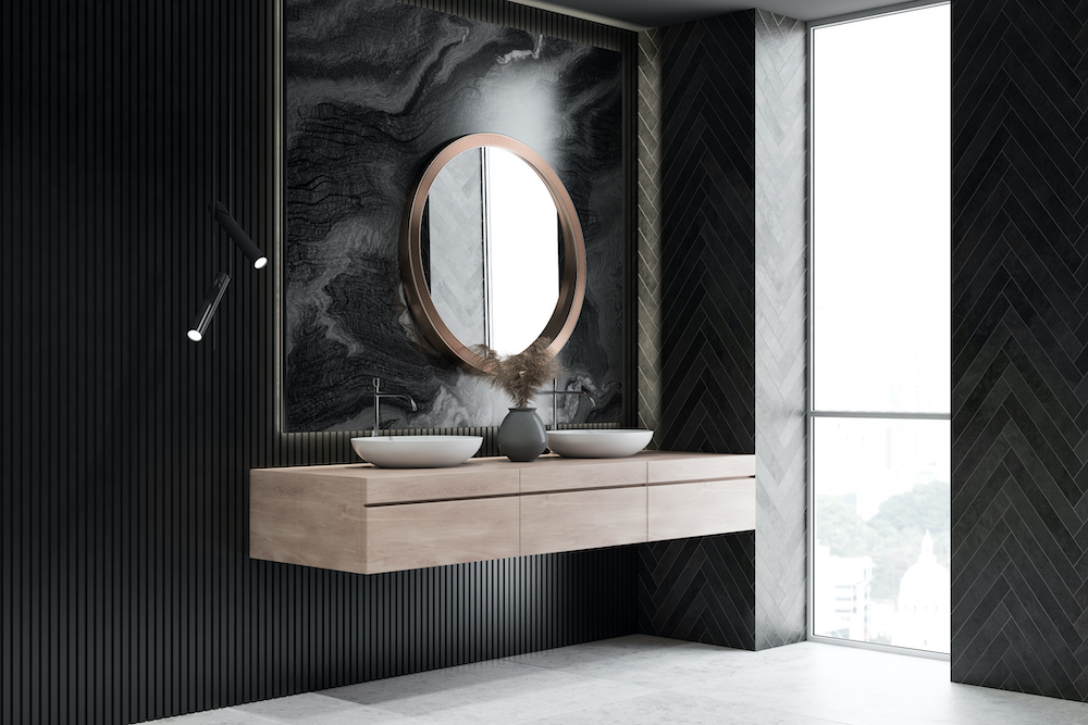Modern design bathroom interior with circle mirror black walls, grey floors, a large floor to ceiling window, and beige floating vanity with two circular vessel sinks