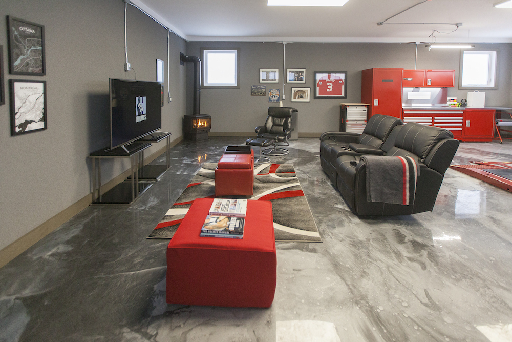 An entertainment centre with a large TV and red and black seating in a modern renovated garage