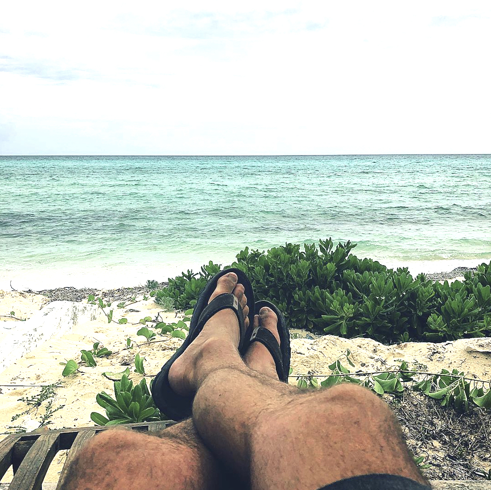 Bryan Baeumler sits on a beach looking out of the Caribbean ocean