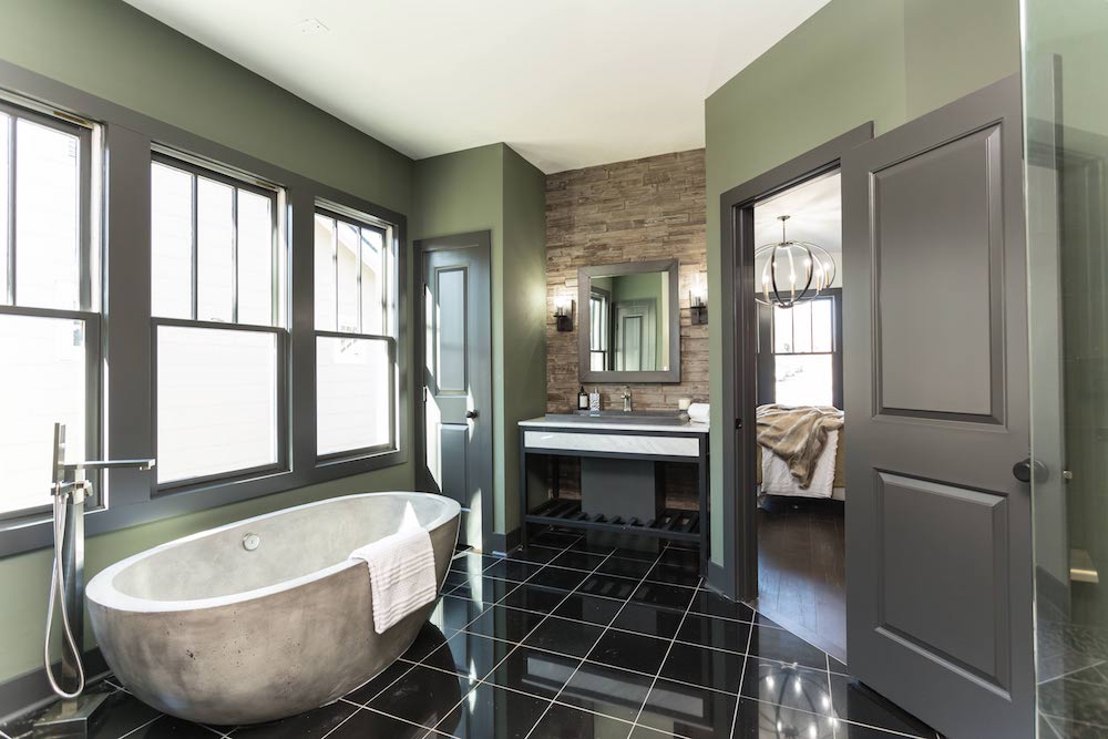 Masters of Flip luxe lodge master bedroom ensuite with concrete bathtub and black square tiles