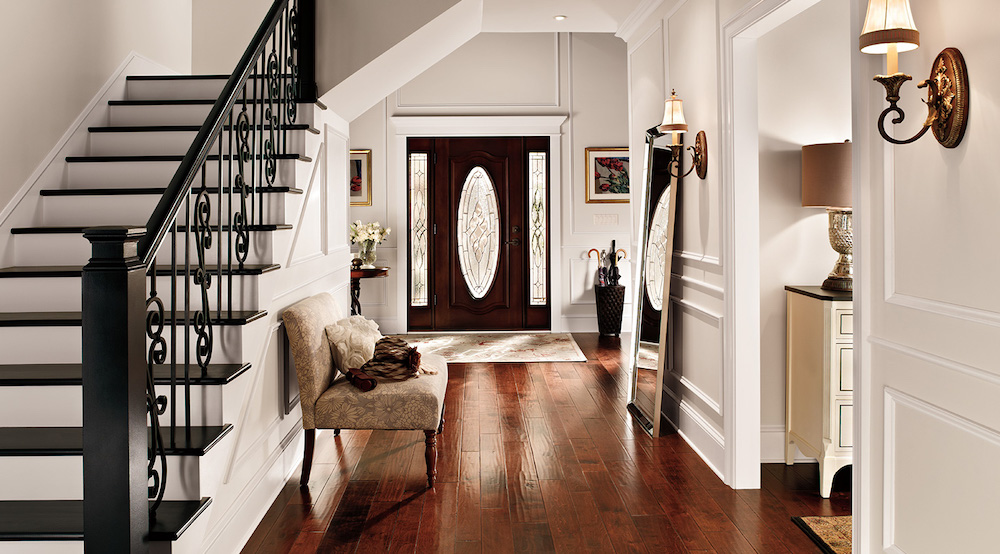 A crisp white entryway in a traditional home with dark wood floors, a front hall bench seat, large hall floor mirror, ornate staircase, and walls painted in BEHR Bleached Linen PPU5-09, Polar Bear 75 and Creamy Mushroom PPU5-13
