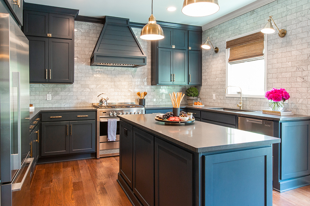 Beautiful renovated kitchen with dark blue cabinets, grey counter to ceiling stone tiles, and a large centre island