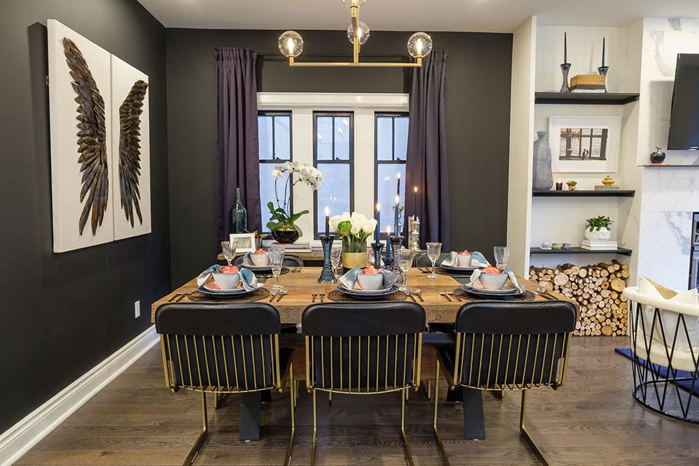 Matte black walls in the dining room set off wing-covered canvases, purple curtains and a thick wooden dining table