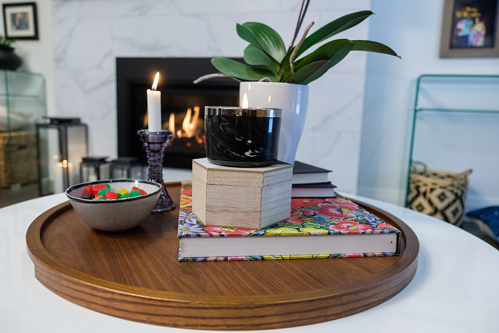 Wooden tray with jujubes, candles, an potted orchid and a flower covered book