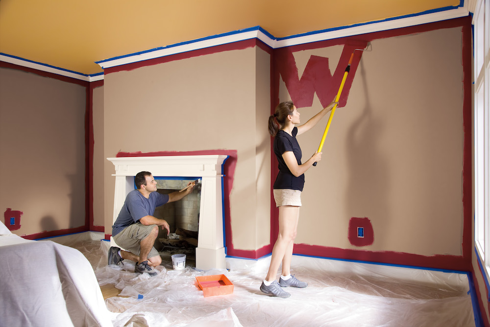 Man painting wall with paint roller near ladder