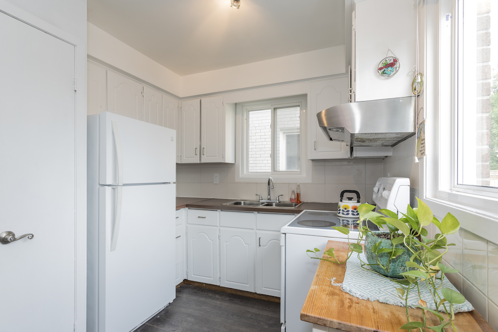Dated white kitchen with white fridge and cabinets