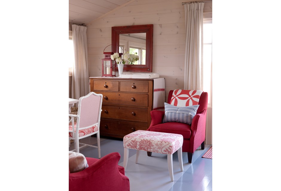 A red and white themed cottage living room with plush furniture
