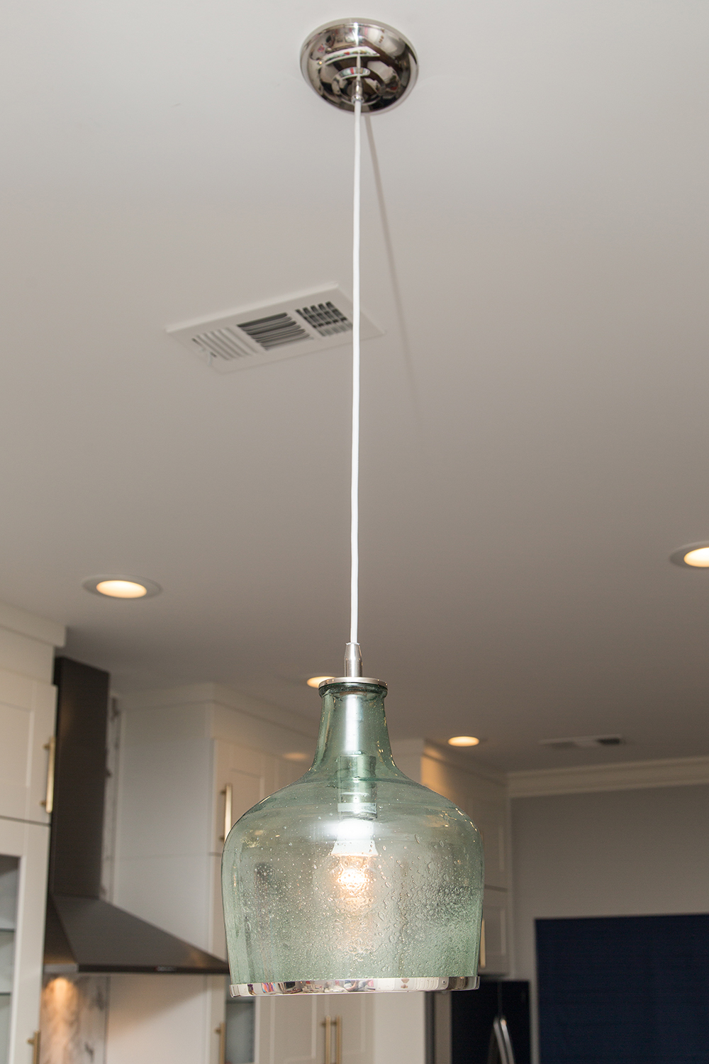 Glass pendant lights hanging over kitchen island