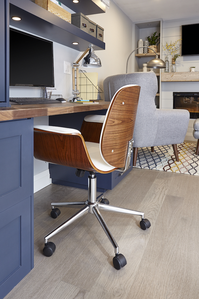 Wood veneer office chair beside a wooden topped desk and navy blue cabinet set