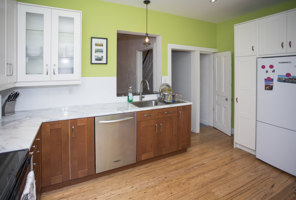 An outdated lime green kitchen with mismatched cabinets and quartz countertop