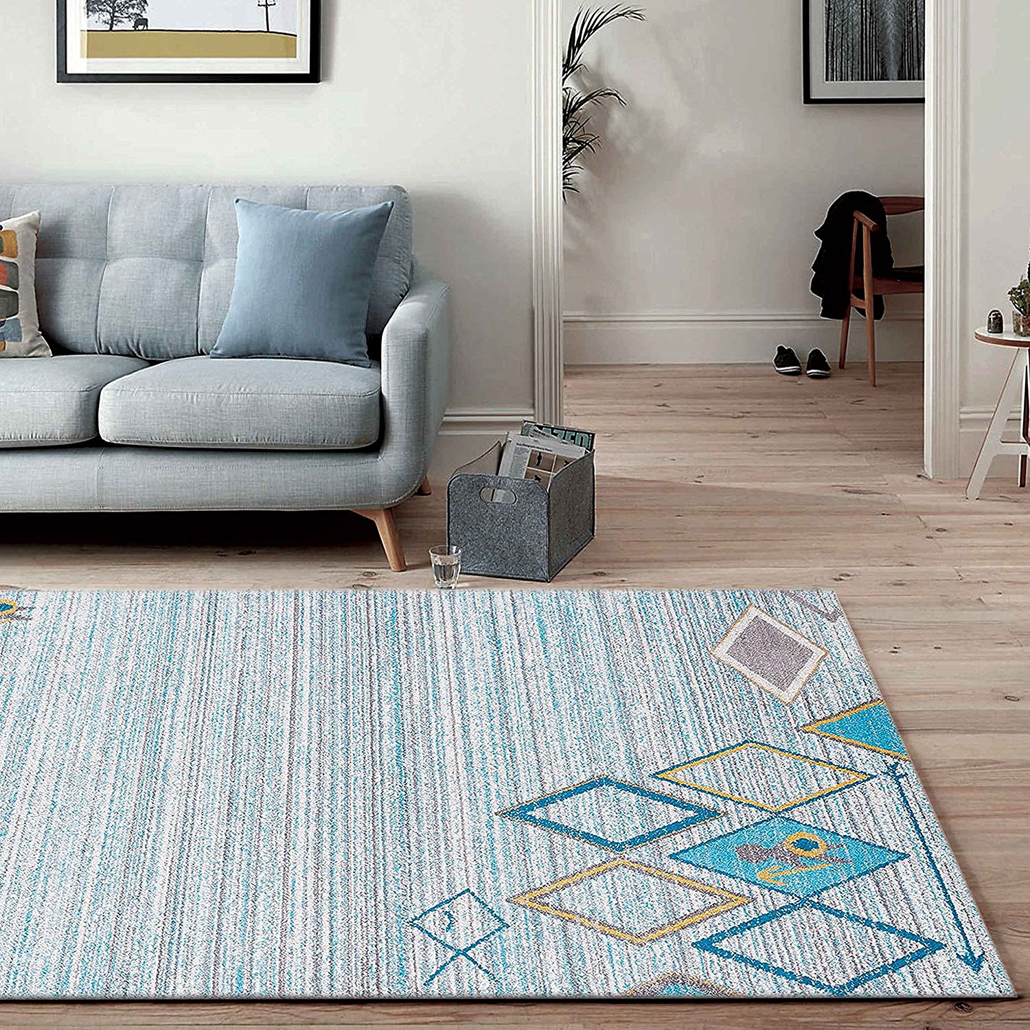 A bright patterned luxury area rug in a living room featuring hardwood floors, grey sofa and a doorway leading to the entryway