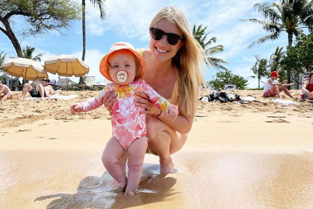 Jasmine Roth smiling on the beach her with baby daughter Hazel