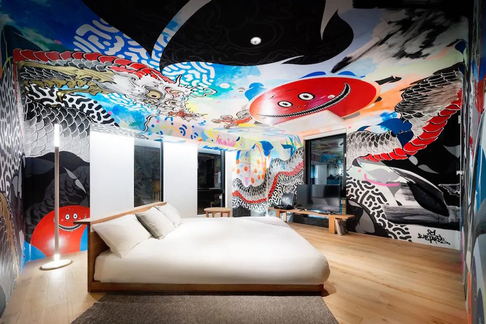 white bed in room with colorful art painted on walls