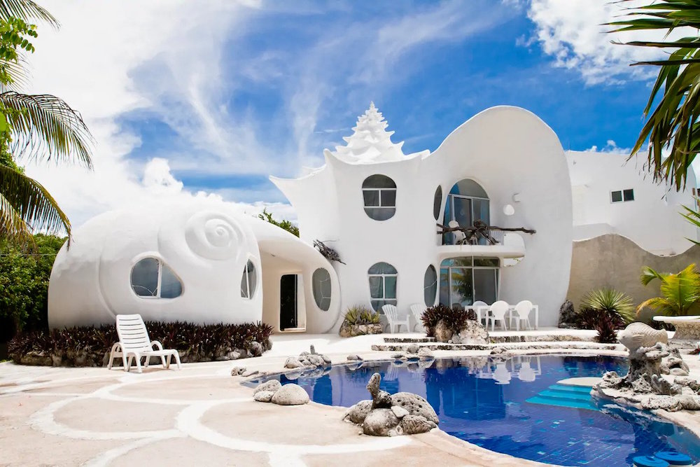 white seashell-shaped house with blue pool