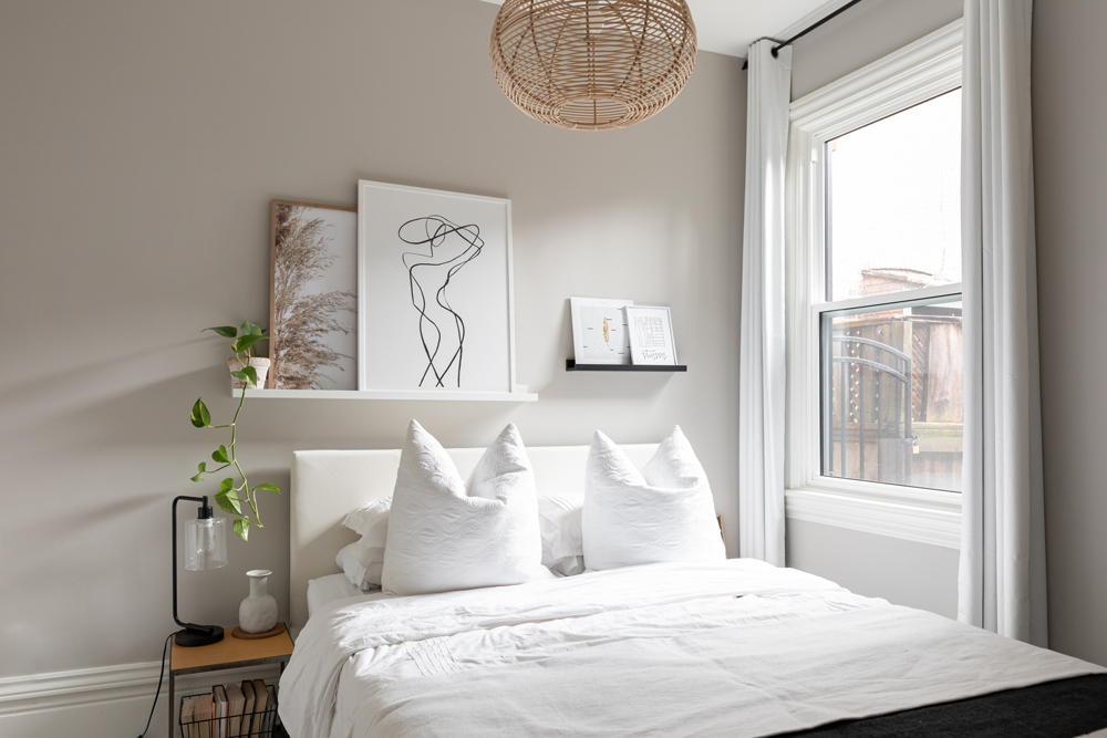 Bedroom with white bedding and artwork on floating shelves