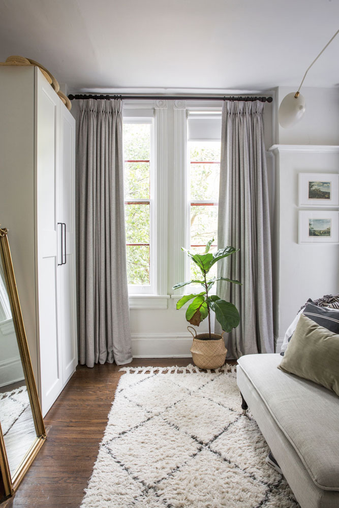 one set of bedroom windows with grey drapes and potted plant in front
