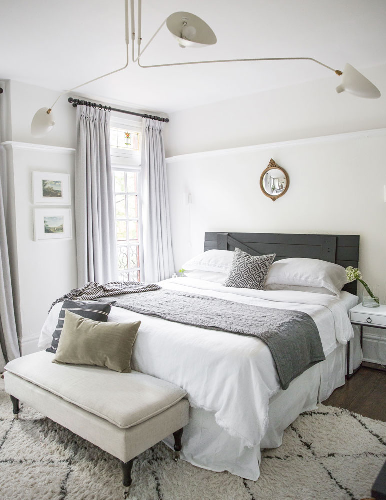 grey and white master bedroom with grey barn door headboard and tiny convex mirror over bed