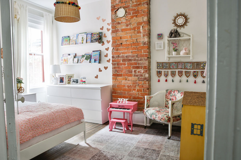 girl's bedroom with exposed brick chimney and little pink piano