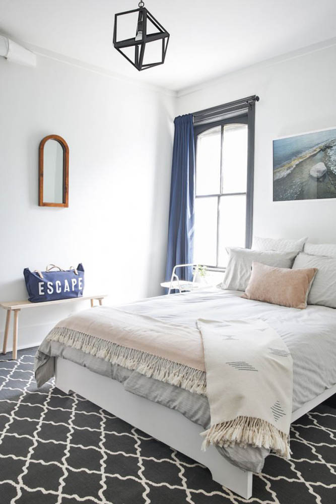 White and blue bedroom with artwork above bed