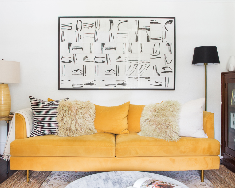 Living room with yellow couch and black and white artwork